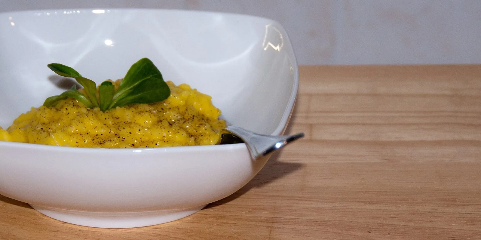 Piatto di risotto alla milanese allo zafferano in una ciotola bianca su un tavolo di legno