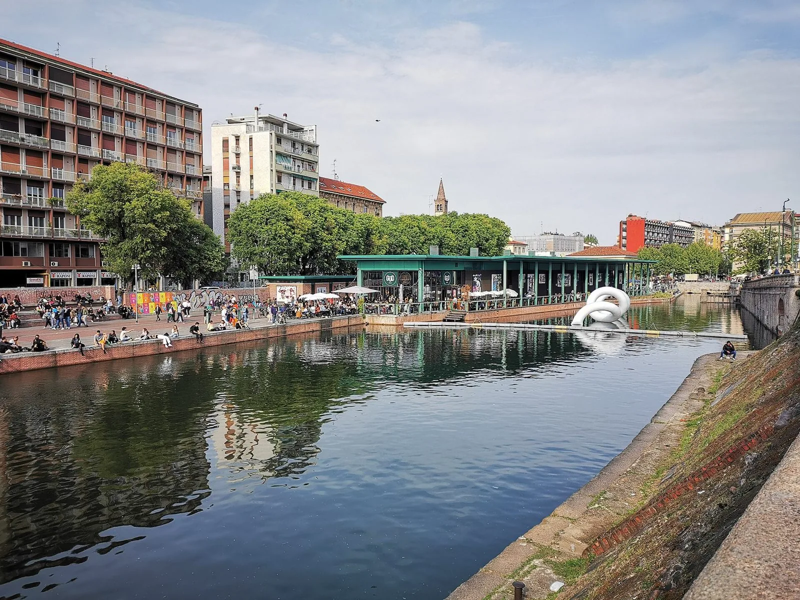 Installazione bianca a forma di anello sull'acqua della Darsena di Milano durante il Fuorisalone